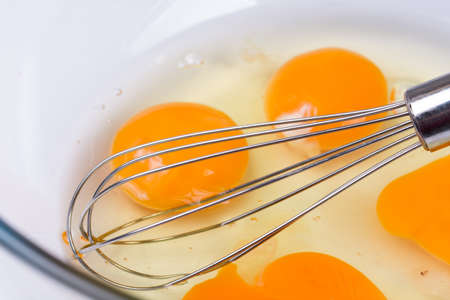 Mixed whisked eggs with wire isolated over whiteの写真素材