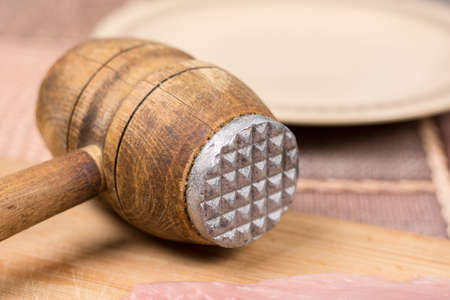 Old retro wooden meat hammer with pork chop on the wooden boardの写真素材