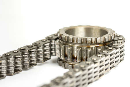 Used oiled timing chain on crang shaft isolated over white background.