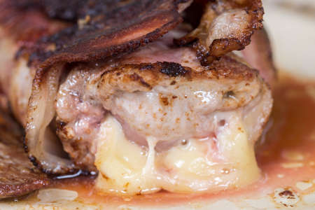 Slice of steak stuffed with yellow cheese rolled in bacon