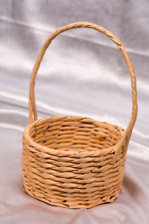 Woven basket for flower arrangement over white satin. Beautiful background for romantic wedding birthday invitations.の写真素材