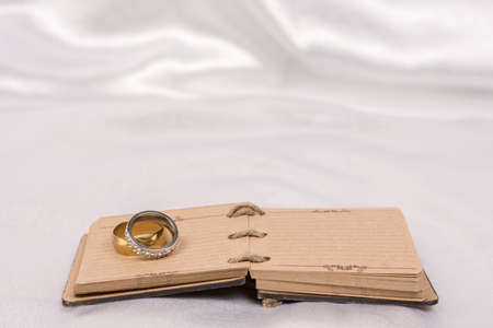 Wedding rings on rustic note paper over white satinの写真素材