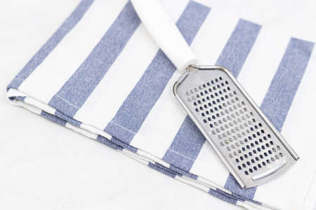 Hand cheese metal grater on the kitchen dishtowel.