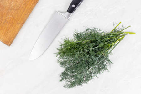 Fresh Dill on the grey marble table with knife in the background.