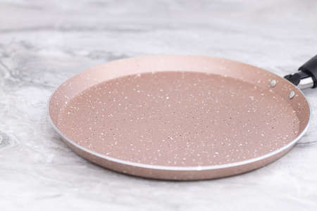 New frying pan on the grey marble table.