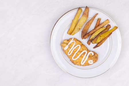 Fried Chicken breasts served with french fries on the plate.