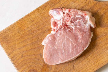 Raw Pork Chops on the wooden cutting board.