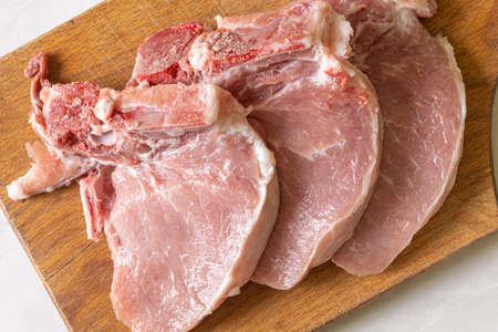Raw Pork Chops on the wooden cutting board.