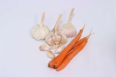 garlic and garlic cloves, and orange carrots on a white backgroundの写真素材