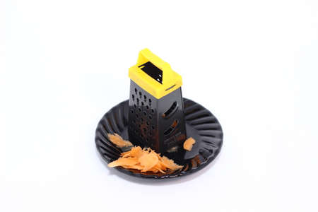 grater and carrots on a plate of glass dark color on a white backgroundの写真素材