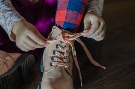 the girl ties the laces on her shoes, in red tightsの写真素材