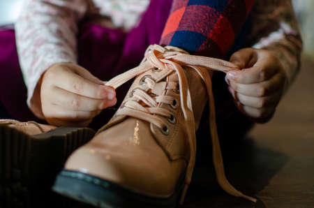 the girl ties the laces on her shoes, in red tightsの写真素材