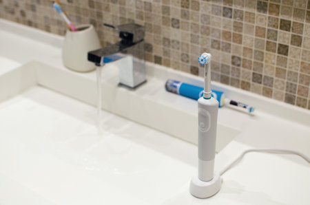 Rechargeable, electric toothbrush, close-up. Against the backdrop of a bathroom in white.の写真素材