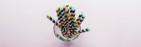 Drinking Straws. Colored paper cocktail tubes on a pink background. In a glass cup. View from the top, close-up.の写真素材
