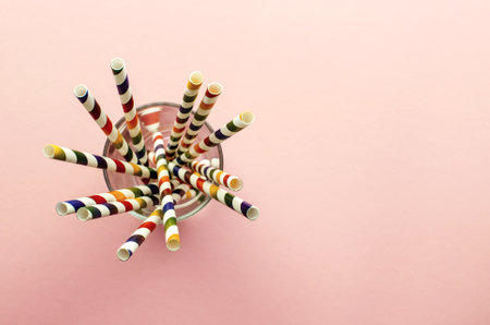 Drinking Straws. Colored paper cocktail tubes on a pink background. In a glass cup. View from the top, close-up.の写真素材