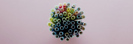 Drinking Straws. Colored paper cocktail tubes on a pink background. In a glass cup. View from the...