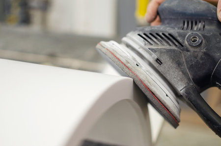 Grinding machine.Worker grinds a wooden part with a hand sanderの写真素材
