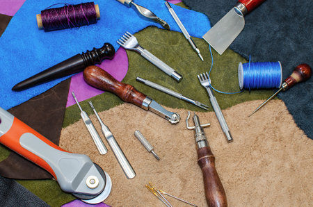 A craft tool for working with leather. Unfolded on colored leather patches. Close-up.