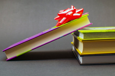 Books wrapped with colored tape on table against dark background. Copy space.の写真素材