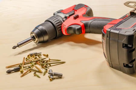Red cordless drill on a black background. Screw tightening tool