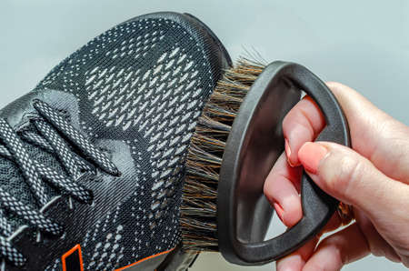 cleans sports shoes, woman cleans shoes with a brush. Sneakers after running.