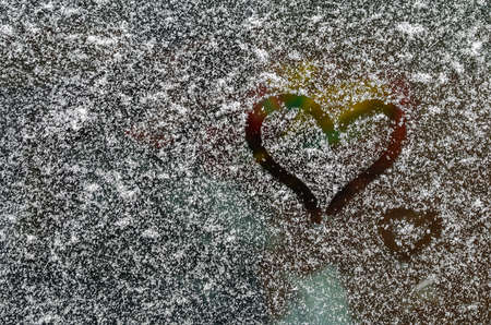 A finger-drawn heart on a snow-covered car windshield. LGBT. Valentines Day concept. Valentines day creative background. Copy space for text.の写真素材