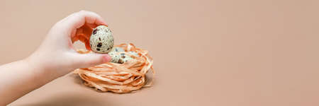 Natural colored quail eggs in the hands of a child, copy space. Easter theme. Place for text