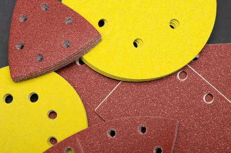 Sandpaper for sanding wood, on a black background. A stack of yellow round sandpaper. Copy spaceの写真素材