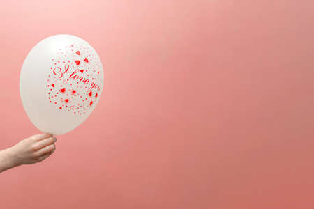 Valentines card with place for text. Balloon with the inscription love in the childs hand. On a pink background.の写真素材