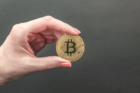 bitcoin in hand, female hand holds a gold bitcoin coin. Cryptocurrency value, digital money, space for textの写真素材
