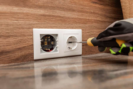 Installing electrical outlets. The electrician installs a decorative frame on the electrical outlets. Screwdriver in the hands of a master installing a socket with glovesの写真素材