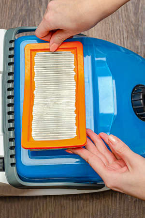 Manual replacement of the air filter in a modern washing vacuum cleaner. removes the filter of the vacuum cleaner by hand.の写真素材