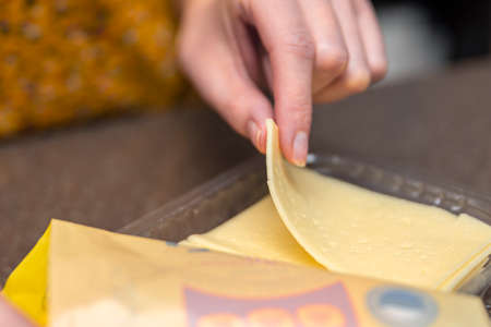 Opens a bag of sliced cheese, a woman opens a bag of cheese, cheese packagingの写真素材
