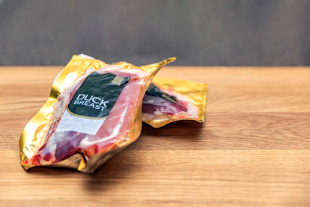 Vacuum packed duck breast. Duck meat in vacuum plastic packaging on a wooden cutting board,...
