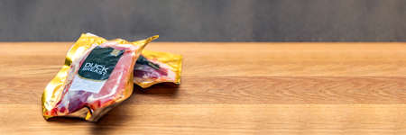 Vacuum packed duck breast. Duck meat in vacuum plastic packaging on a wooden cutting board,...