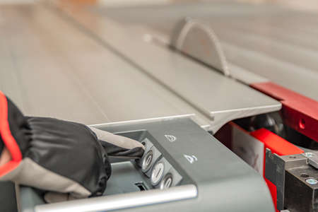 Hand presses the button turning on an industrial machine. Cutting saw blade. Switches for...