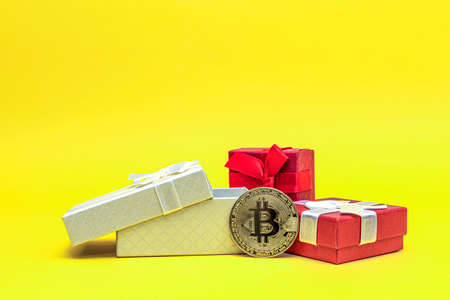 Bitcoin as a gift. Investment gift Bitcoin coin in a gift box on a yellow background. Postcard for printing, banner with place for text.の写真素材