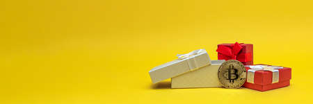 BTC gift. Bitcoin coin in a gift box on a yellow background. Postcard for printing, banner with place for text.の写真素材