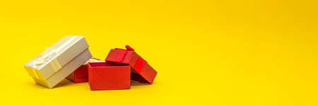 Gift boxes on a yellow background, banner. Red gift boxes, open box. Postcard for printing, banner with place for text. panoramic photo, large size, empty space for congratulations or designの写真素材