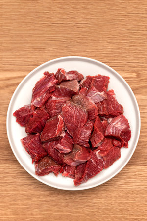 Cooking pilaf in a cauldron, a recipe for real pilaf. Ingredients for cooking pilaf on a wooden background. Raw meat on a wooden cutting board, cut into piecesの写真素材