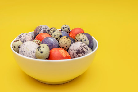 Multicolored easter eggs close up, brightly colored chicken eggs for easter, on a yellow background, greeting card, place for text.の写真素材