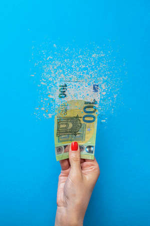 Euro inflation. Inflation in Europe, hyperinflation. Banner with blue background. One hundred euro banknote sprayed in the hand of a man on a blue background.の写真素材