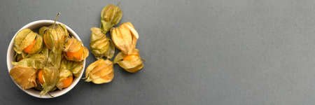 Physalis fruits against black background. Sweet yellow physalis berries in a cup on a dark table top, place to insert text or designの写真素材