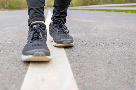 Morning run. Running feet while running, Runner in black sneakers runs on the asphalt.の写真素材