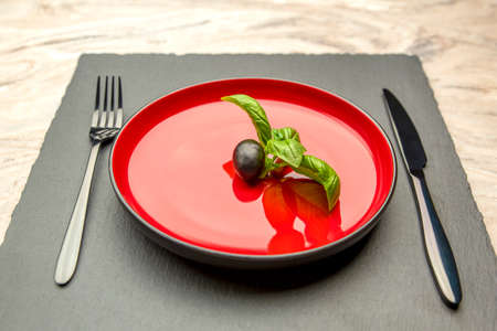 Diet. Small amount of food on the plate. One olive is in a red plate, a knife and a fork. Weight loss and diet concept. Empty space for textの写真素材