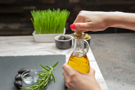 Olive oil. A woman pours olive oil into a saucer.の写真素材