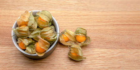 Physalis fruits on a wooden table. Sweet yellow physalis berries in a cup on wood backgroundの写真素材
