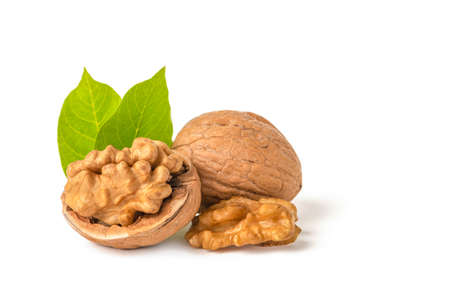 Walnut fruits lie on a white isolated background. Peeled walnut and green leaves with shadow. White...