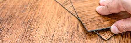 Choice of flooring. Renovation or construction concept. Close-up of a male hand holding a textured...