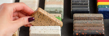 A woman chooses stone samples for a kitchen countertop. A set of multi-colored samples of artificial acrylic stone.の写真素材